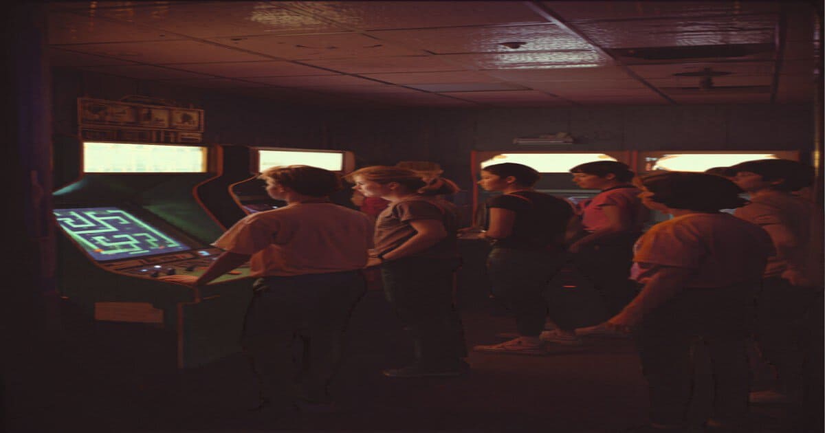 Teenagers in 1980s fashion gathered around arcade game machines in a glowing 1980s arcade hall