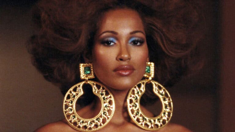 1980s glamorous woman with large gold door-knocker hoop earrings, big permed hair and bold makeup