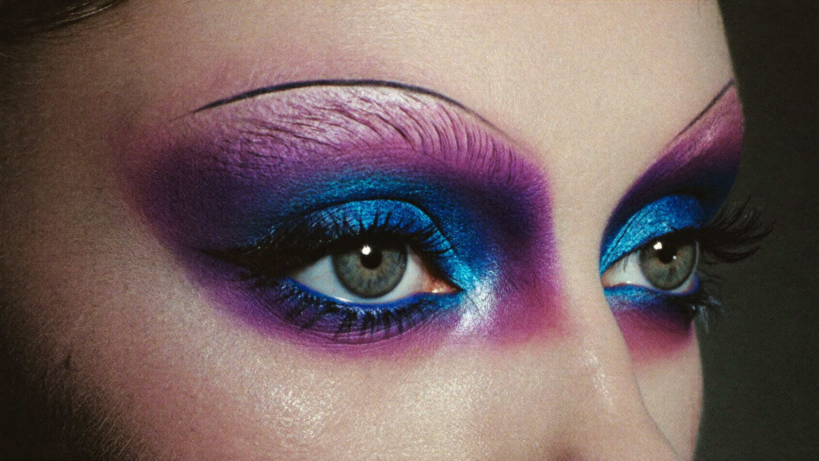 Close-up of dramatic 1980s punk eye makeup with electric blue eyeshadow and heavy black kohl liner