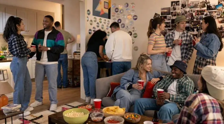 Adults enjoying a realistic 90s-inspired house party with denim outfits, snacks, games, and a photo wall