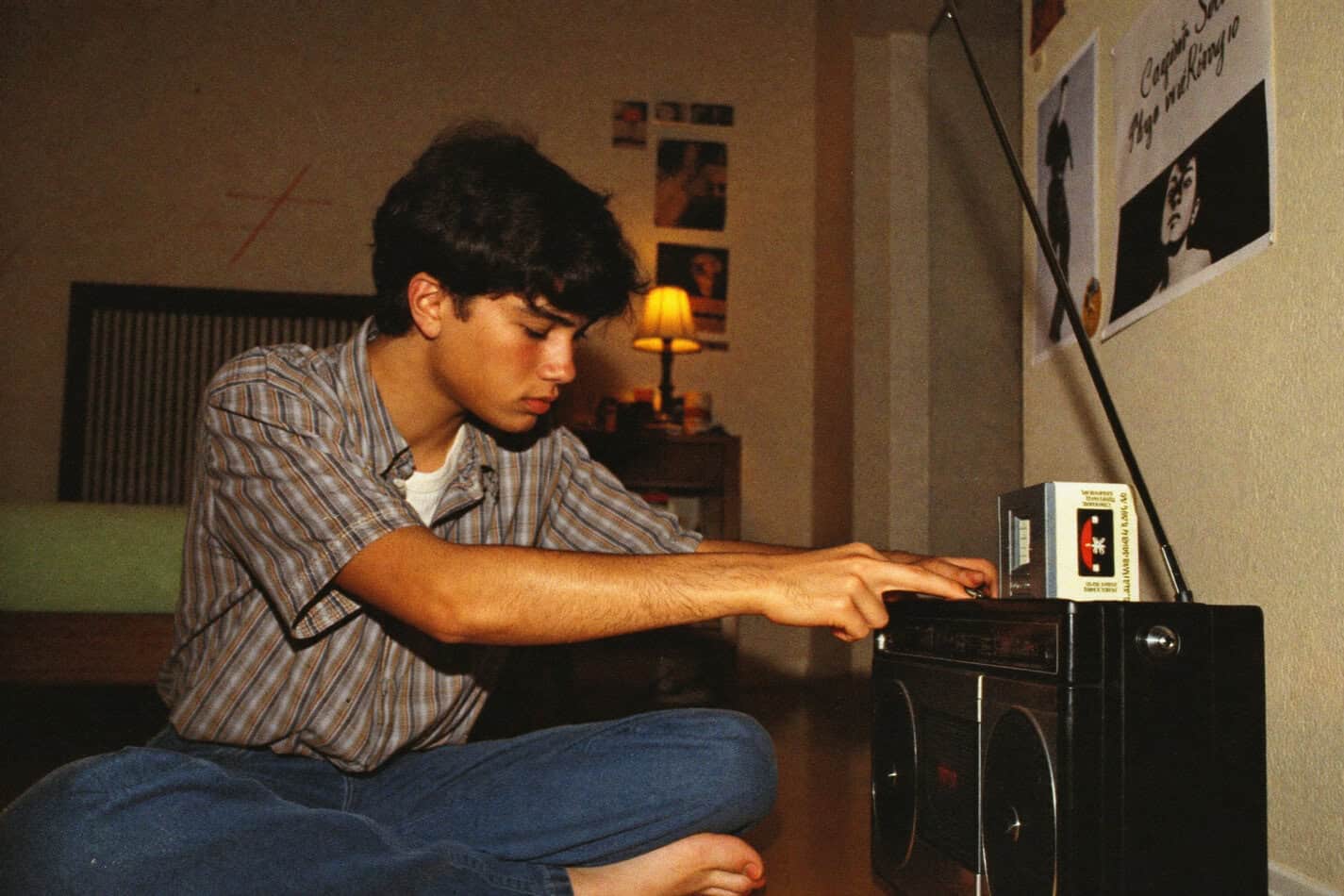 1980s teenager recording songs off the radio onto cassette tape with boombox