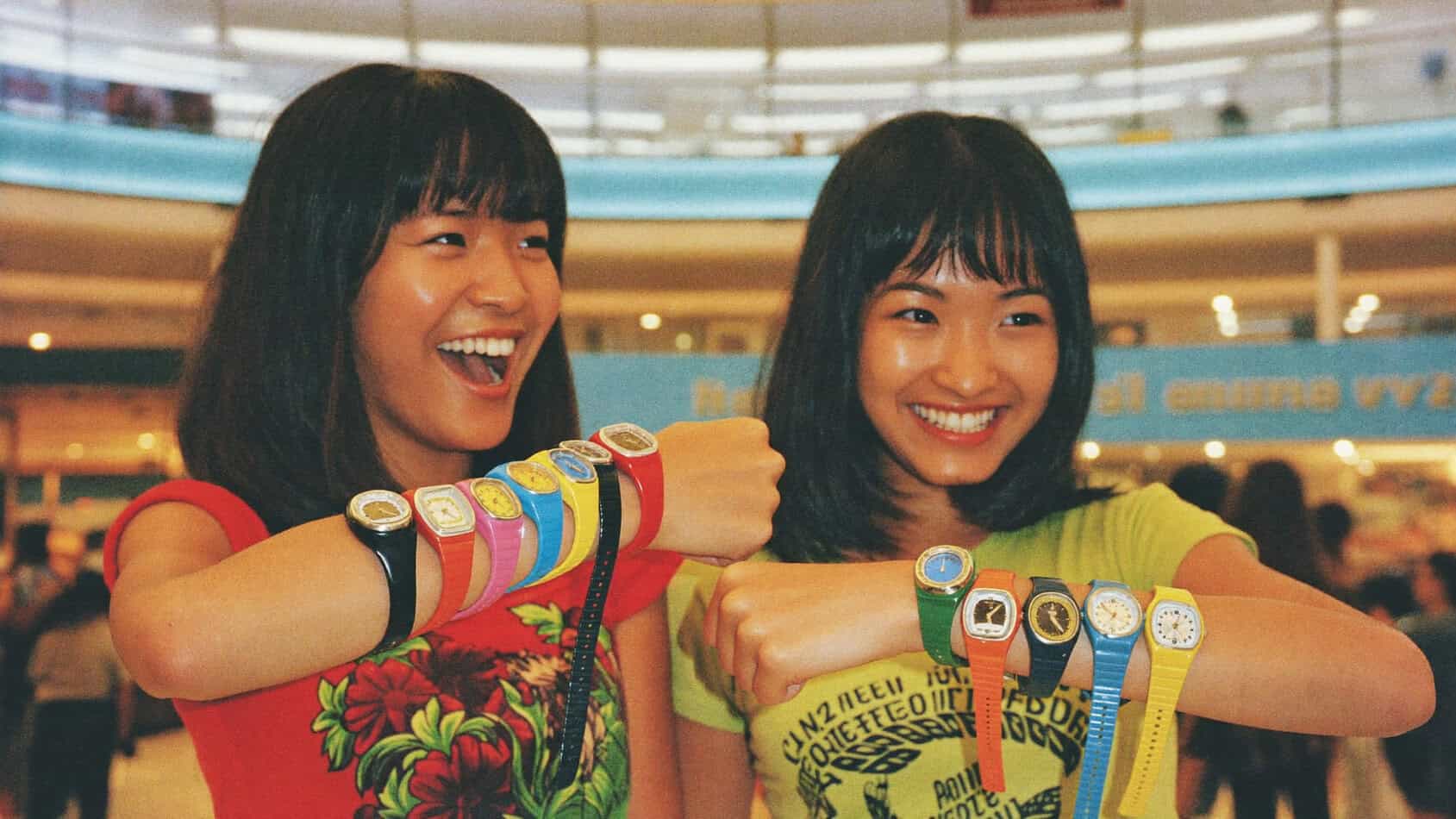 Teenage girls at the mall in the 80s showing off stacked Swatch watches on their forearms